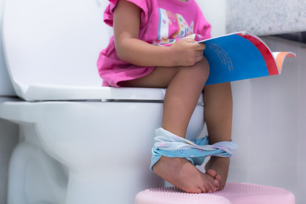 little girl potty training and reading a book