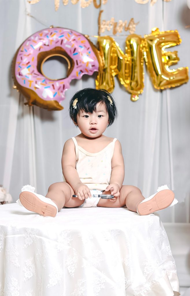 baby's sitting in front of One balloons for her first birthday