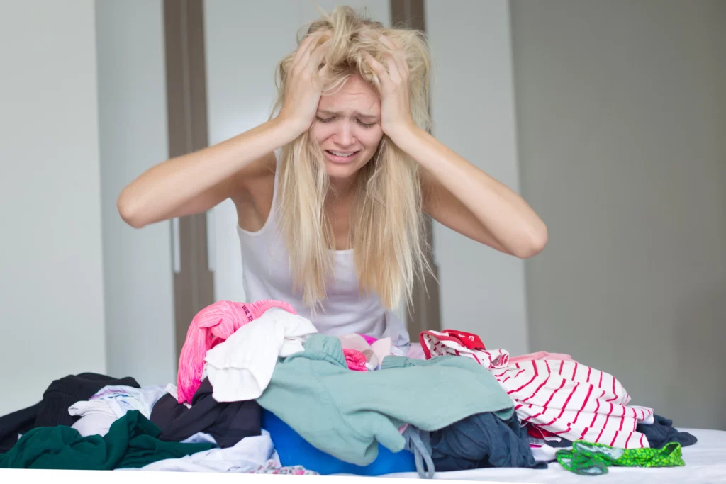 mom holding her head in agony looking stressed over a pile of laundry