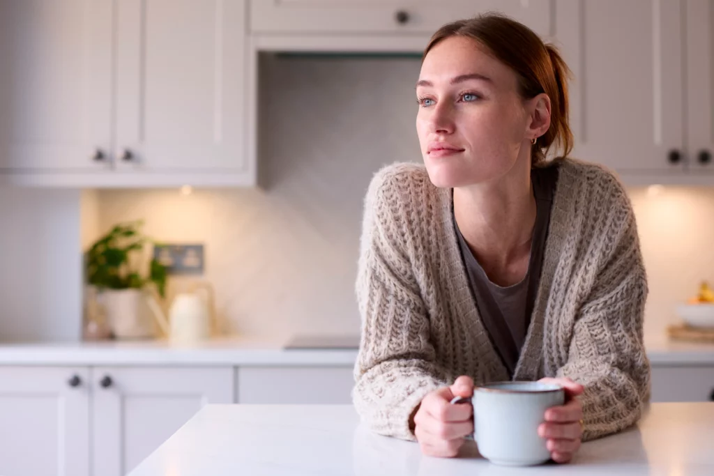 woman appearing satisfied in clean kitchen with mug in hand