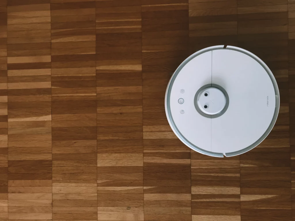 White robot vacuum on wooden floor