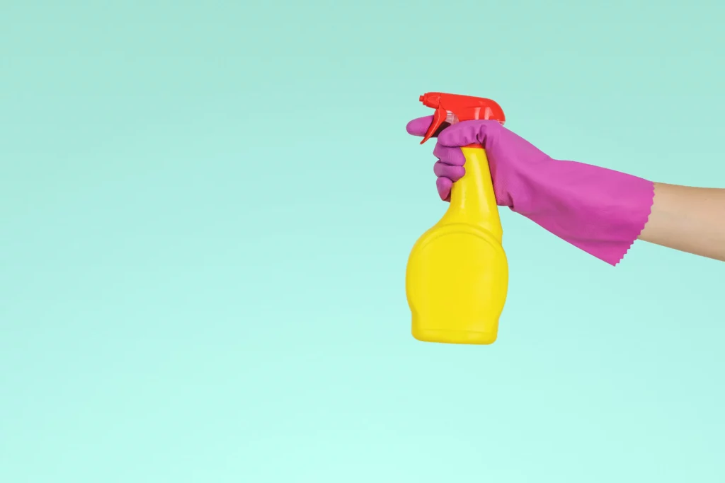wearing cleaning glove and holding yellow spray bottle