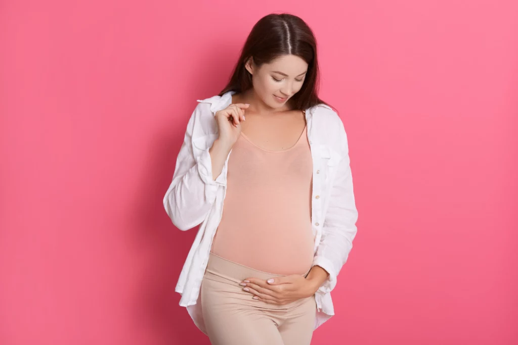 Woman looking at belly in workwear