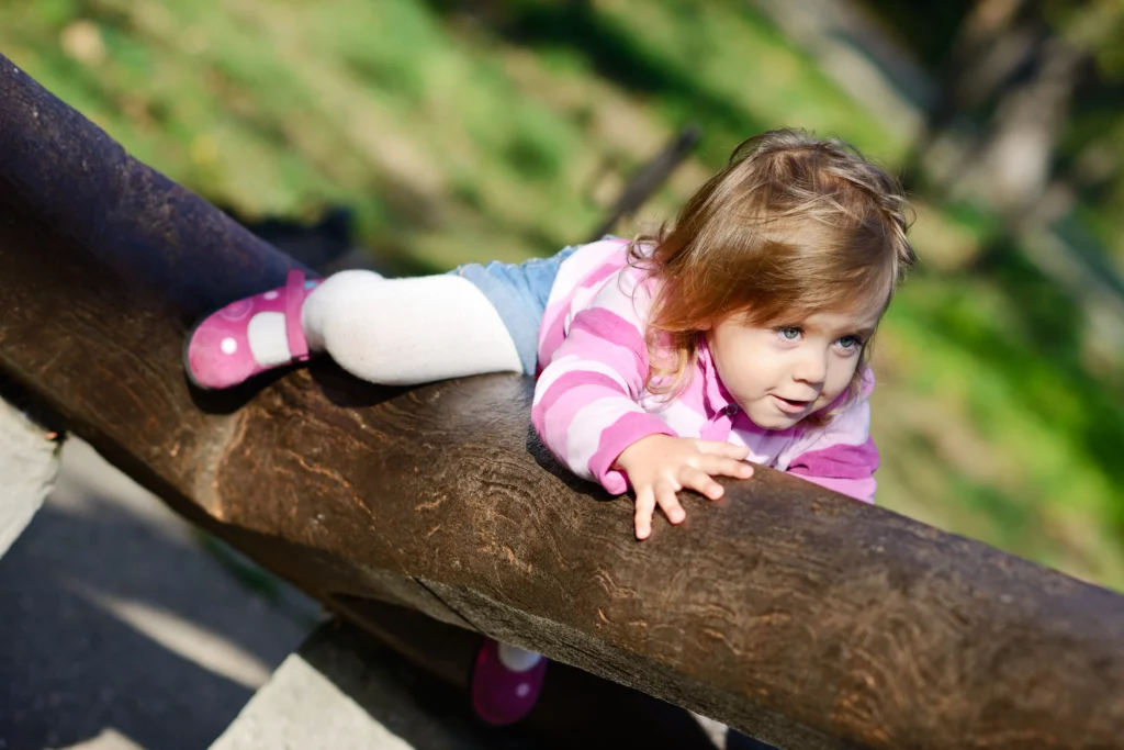 Toddler girl climbing on tree as a fun backyard activity 