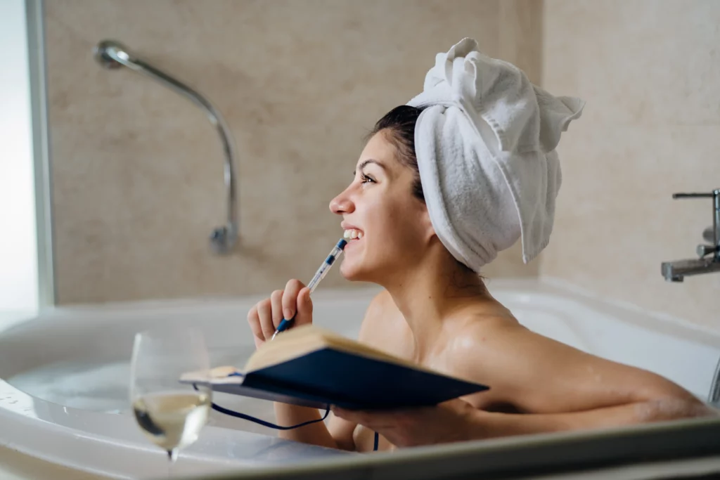Smiling woman taking a relaxing bath and journaling