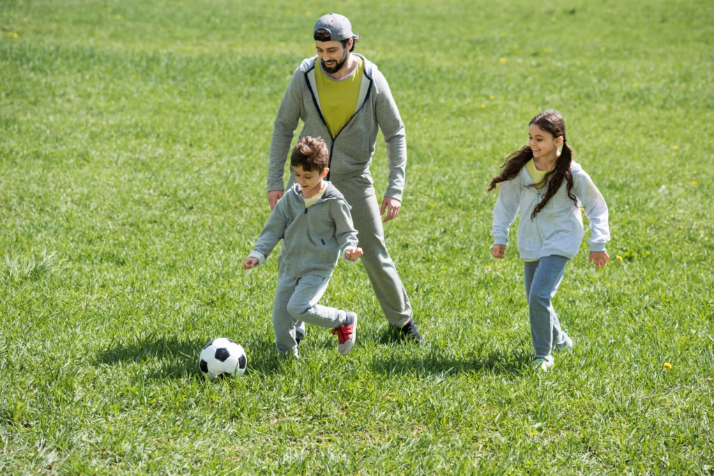 Dad playing soccer with kids