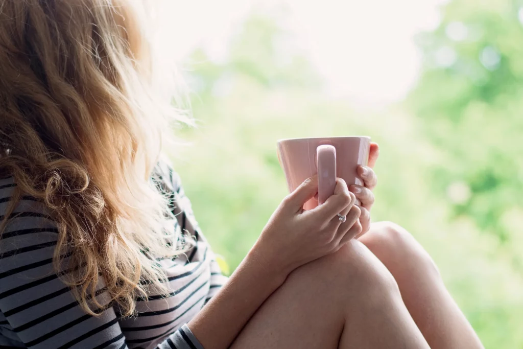 Woman relaxing starting at nature while sitting with a cup of coffee